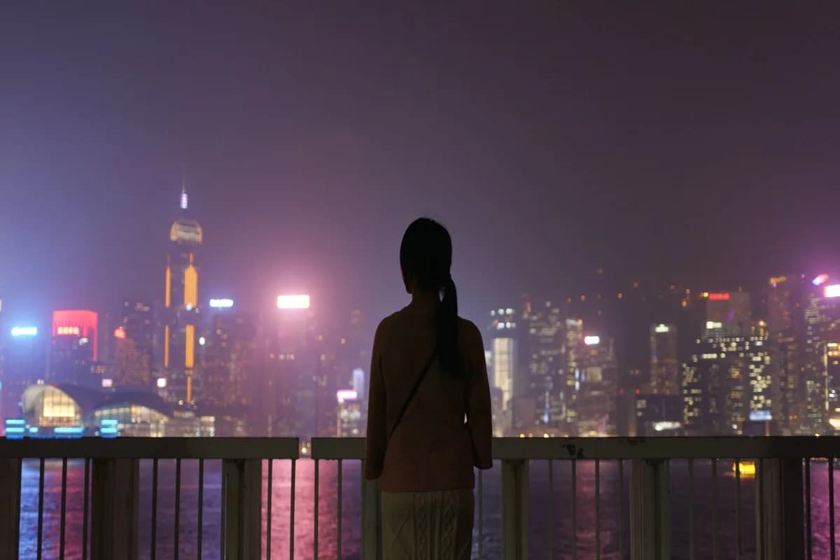 A person standing alone at night looking at city lights — the profound aloneness of the Dark Night of the Soul