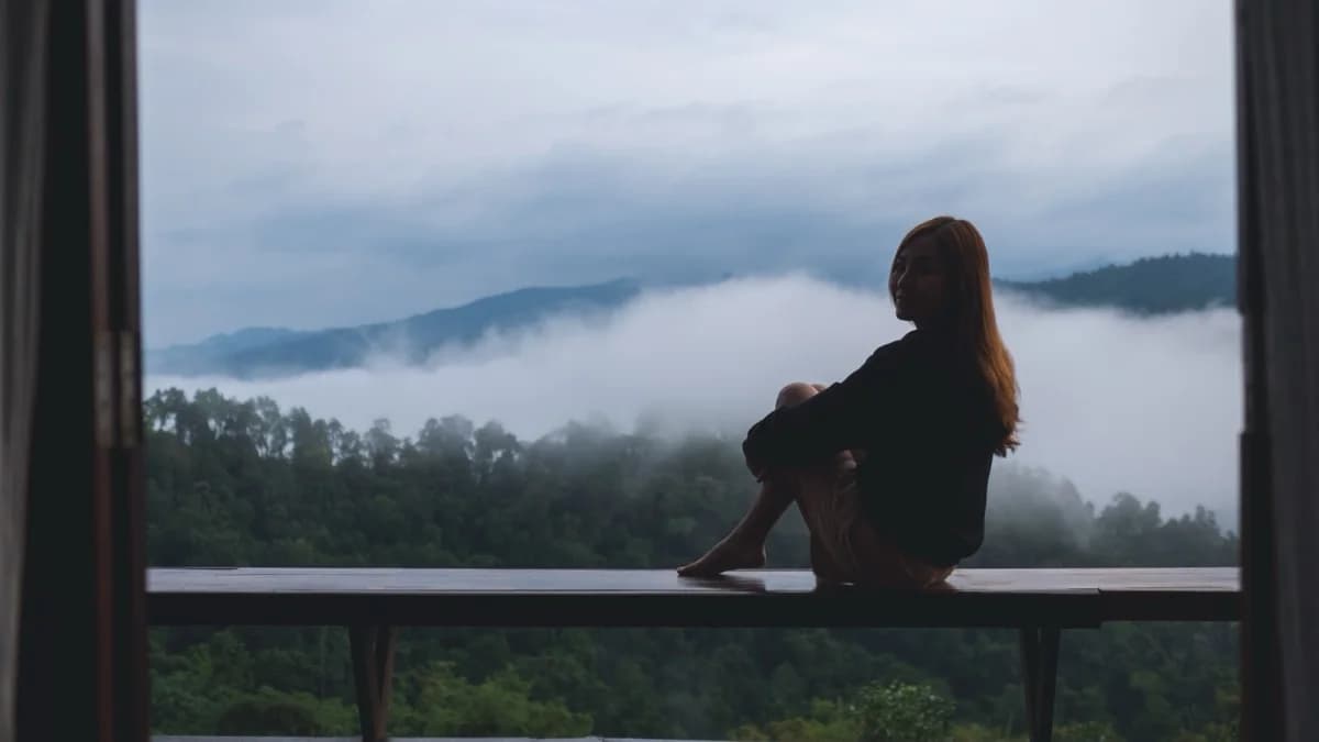 A person sitting by a window during a soft overcast morning, looking out thoughtfully — the honest weight of emotional struggle
