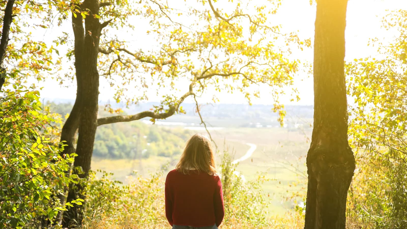 Person sitting alone in quiet contemplation by a window in soft morning light