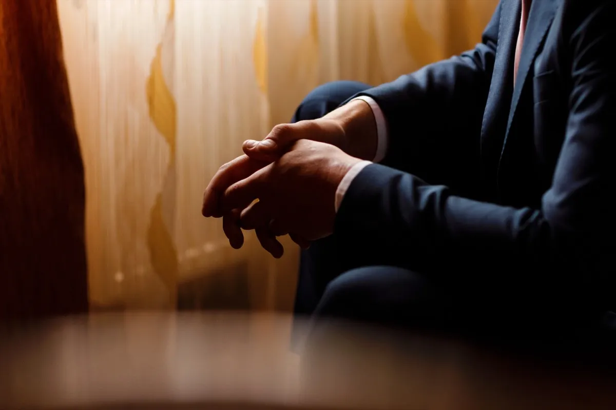 A person sitting with clasped hands — outwardly composed, inwardly in turmoil