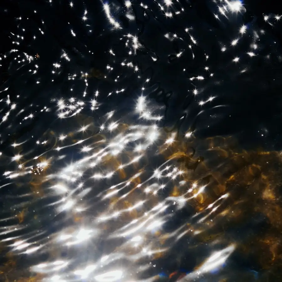 Shimmering light rippling across the surface of dark water, representing the multiple hidden layers of emotion and ancestral patterns that surface during the Dark Night