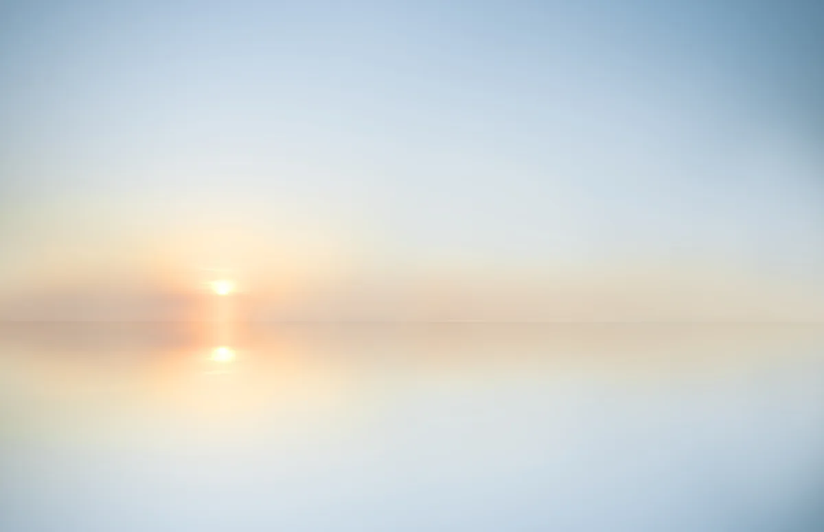 Dawn light breaking softly over a peaceful landscape